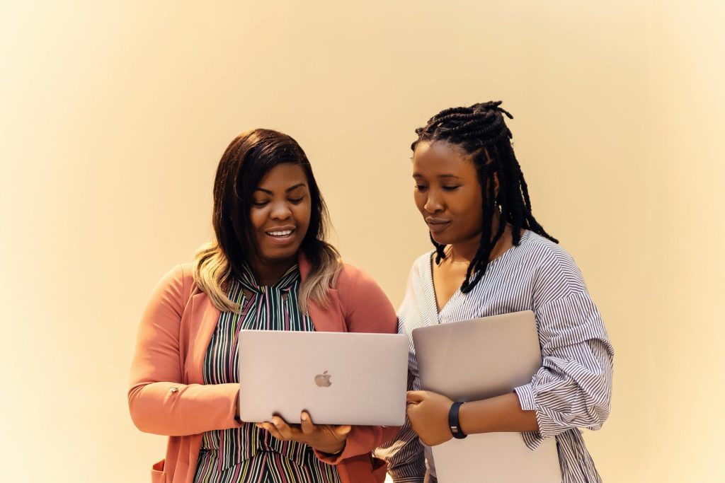 Two professional women collaborating with laptops in Lagos, Nigeria.